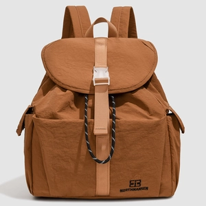 Detail of caramel nylon backpack showing flap cover with white buckle and logo