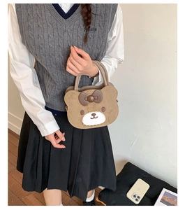 Detailed view of a brown plush bear handbag with a dark brown bow and embroidery