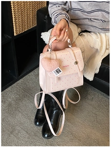 Detailed shot of a pink polka dot children backpack with a plush heart charm on a sofa