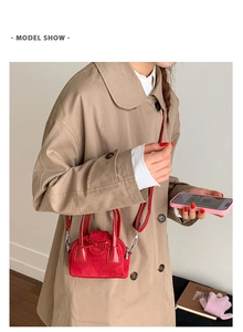 Detail showing red mini crossbody bag with suede texture and bow decoration on a trench coat