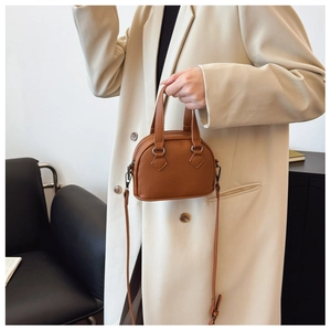 Detailed view of caramel brown shell-shaped mini handbag with crossbody strap
