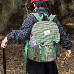 Kids outdoor hiking backpack with green plaid pattern shown on a child in a forest