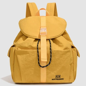 Detail of yellow nylon backpack featuring buckle closure and drawstring texture