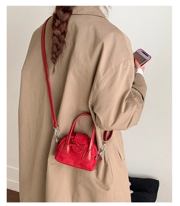 Red mini bowling bag with bow detail worn as a crossbody by a model in a trench coat