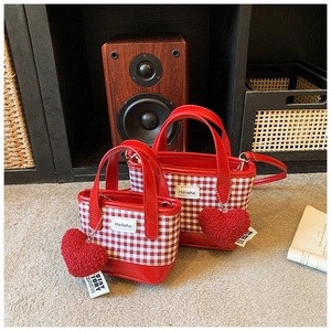 Detail of red and white checkered tote bags featuring plush heart charms and leather trim