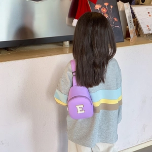 Child model wearing a purple crossbody chest bag with yellow towel embroidered letter E