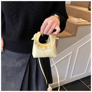 Detail of yellow tote bag featuring lace trim stitching and delicate shoulder strap