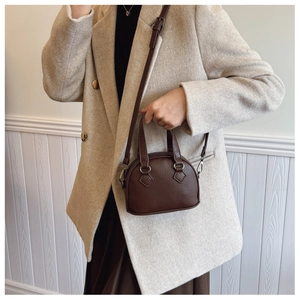 Detailed view of brown lychee texture shell bag with adjustable strap and dual handles