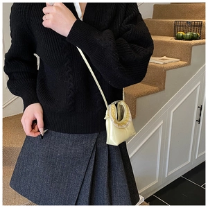 Detail of yellow satin mini bag featuring delicate lace ruffles and a slim shoulder strap