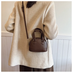 Brown lychee leather shell bag with adjustable strap worn as a crossbody for kids