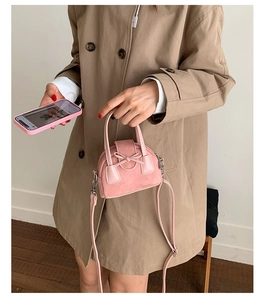 Detalle de mini bolso rosa con lazo en ante sintético con hebilla plateada y correa
