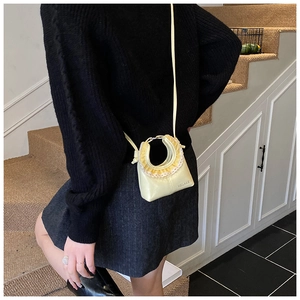 Detail of sweet cream-colored mini bag featuring yellow ruffles and white lace trim