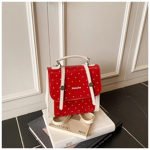 Close-up of a red and white polka dot mini backpack with silver metal buckles