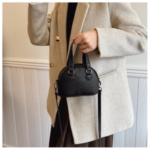 Detail shot of mini black pebble grain leather shell bag with top handle and strap