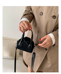 Detail of black suede-textured mini handbag featuring a sleek bow and detachable strap