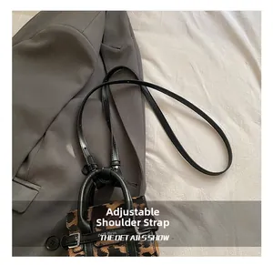 Gros plan d'un mini sac léopard avec une bandoulière réglable en cuir noir robuste