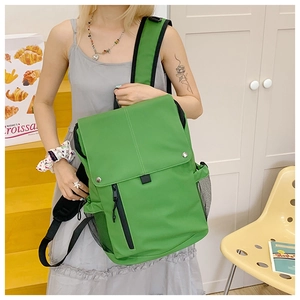 Detail of green nylon school backpack showing front vertical zipper pocket and side mesh pocket