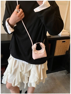 Detail of pink mini leather crossbody bag with white lace trim and adjustable shoulder strap