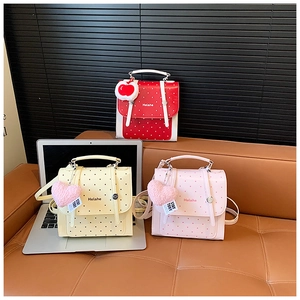 Three colorful polka dot backpacks for children in red, yellow and pink with cute plush charms