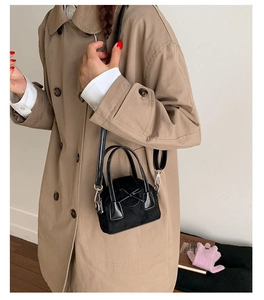 Chic black mini crossbody bag with suede finish and elegant bow detail worn by model