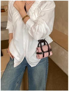 Détail du mini sac bandoulière en daim rose avec poignées en cuir marron et logo