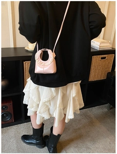 Pink glossy patent leather bag with U-shaped ruffle handle and white lace trim detail