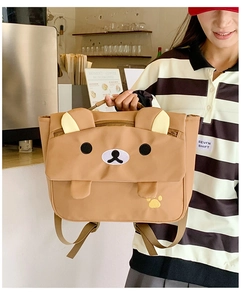 Brown canvas kids backpack with cute bear face embroidery in a warm cafe setting