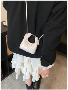Detail of sweet cream mini crossbody bag featuring pink chiffon lace and HELAHE logo