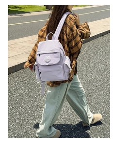 Gros plan du sac à dos scolaire en nylon lilas avec poches multiples en situation réelle