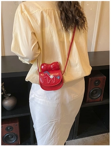 Détail d'un sac à bandoulière matelassé rouge pour enfant avec nœud et broderie