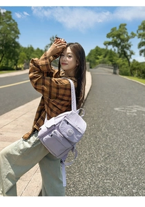 Détail du mini sac à dos en nylon violet clair avec rabat et plaque logo circulaire