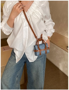 Détail d'un mini sac à main en jean bleu avec garniture en cuir marron et boucle en métal
