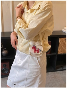 Détail d'un mini sac blanc avec un nœud en cuir et une broderie de poney colorée