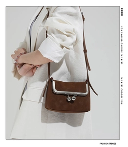 Brown retro suede crossbody bag with silver clasp detail shown on a white blazer