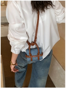 Vue arrière d'un mini sac à bandoulière en denim bleu avec anses en cuir marron sur mannequin