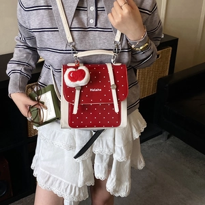 Red polka dot school backpack for kids with a cute plush charm and adjustable straps