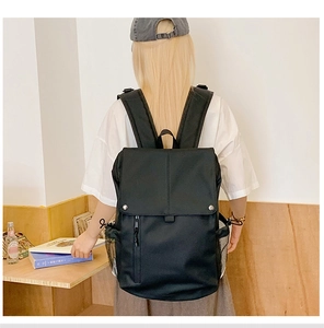 Detail view of large capacity black backpack featuring flap closure and side mesh pocket