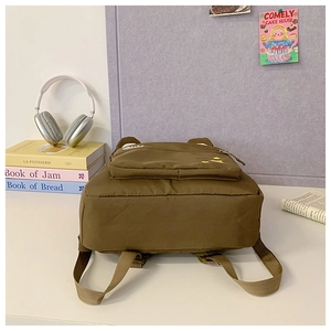 Macro detail of brown children's backpack with yellow crown embroidery and strap