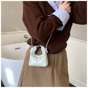 Detail of mint green mini crossbody bag with beige lace trim and BELANE logo on front