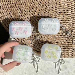 Glittery AirPods case with 3D bows and pearl charms on a woven mat background