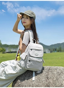 Détail d'un sac à dos en nylon imperméable gris clair porté par un modèle à l'extérieur