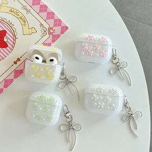 Glittery AirPods case with colorful 3D bows and pearl charms on a clean white background