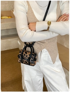 Gros plan du mini sac à main léopard avec bordure en cuir noir et boucle en métal
