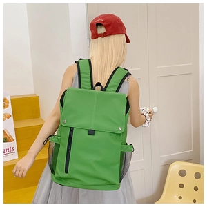 Detail view of grass green backpack featuring magnetic flap closure and mesh side pockets