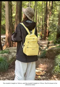 Vista posteriore di uno zaino da trekking giallo con tasche multiple in mezzo alla natura