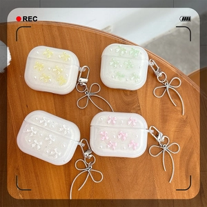 Sparkly AirPods case with 3D bow and pearl charms in multiple pastel colors on wood table