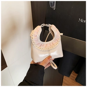Close-up of cream white glossy leather mini handbag with pink lace trim and brand logo