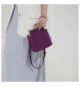 Close-up of purple suede kiss-lock bag with silver metal frame and beaded bracelet detail