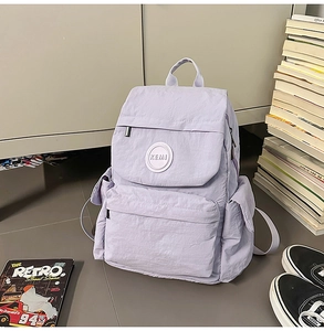 Détail d'un sac à dos en nylon violet clair avec poches latérales et compartiments zippés