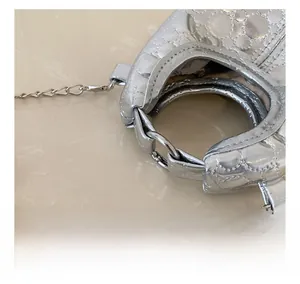 Detail of silver metallic handbag with quilted texture and circular handle